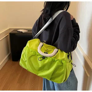 Detail view of a bright green large capacity travel duffel bag with comfortable shoulder strap.