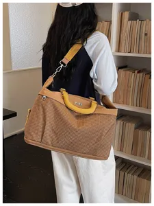 Grande borsa da viaggio con motivo a quadri, manici gialli e tracolla per sport e vacanze.