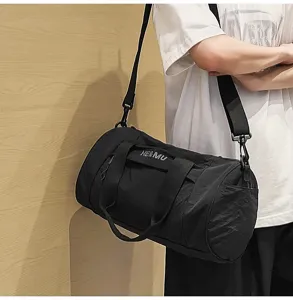 Black cylindrical gym duffel bag detail view, casual shoulder strap and practical daily use.