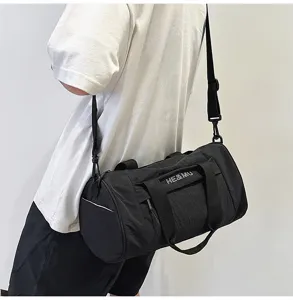 Black cylinder gym duffel bag detail view, portable travel crossbody storage bag for daily fitness.