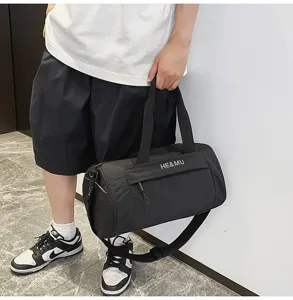 Detail view of black cylindrical sports duffel bag with handle and crossbody strap for gym.