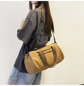Detailed view of the brown cylindrical sports fitness duffel bag worn across the body.