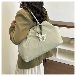 Detail shot of a large capacity canvas tote bag featuring a cute spotted dog pendant and shoulder straps.