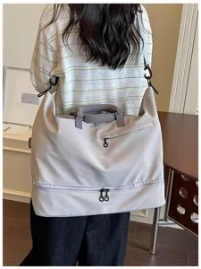 Detail view of large travel duffel bag with bottom compartment, shoulder strap and handle.