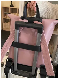 Dettaglio zaino rosa da viaggio con pratica fascia per trolley e manico superiore comodo.