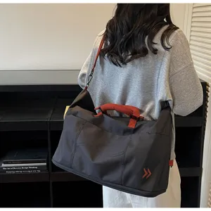 Large capacity travel duffel bag detail, dark grey shoulder bag with red handles for travel.