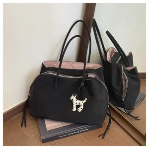 Detailed view of black commuting tote bag with pink lining and cute dog pendant accessory.