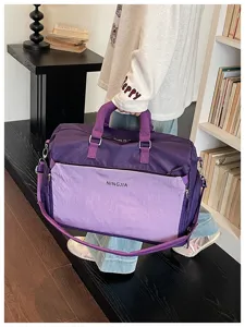 Détail de sac de voyage montrant un tissu violet durable et des poignées confortables.