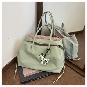 Detail view of light green shoulder tote bag featuring large capacity, cute dog charm and pink interior.