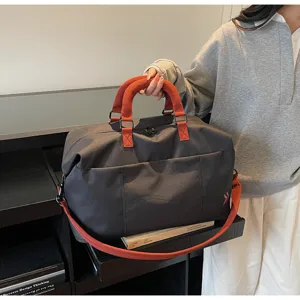 Large capacity travel duffel bag with orange handles and shoulder strap for short trips.