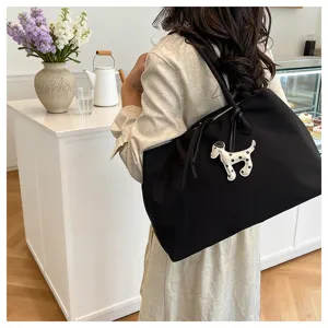 Detail view of the black canvas tote bag showcasing the cute puppy charm and spacious design.