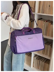 Vue détaillée du grand sac de voyage violet avec bandoulière et poche avant pratique.