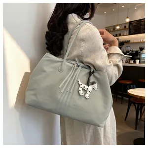 Detailed view of the sage green large capacity tote shoulder bag with cute dog charm.