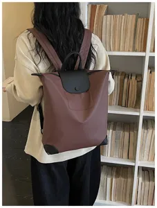 Vista dettagliata di un elegante zaino marrone da viaggio con patta in pelle nera in libreria.