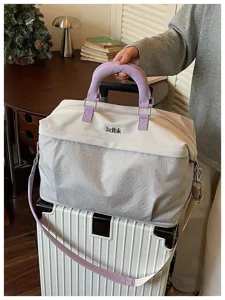 Dettagli della grande borsa da viaggio con manici viola e motivo geometrico elegante.