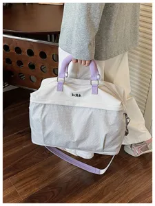 Dettaglio borsa da viaggio con tessuto resistente, manici viola e motivo a quadri.