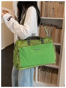 Détail du sac de voyage vert avec poche avant quadrillée, poignées solides et bandoulière.