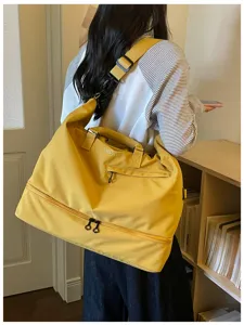 Detailed view of large capacity yellow travel duffel bag worn by model, showcasing strap design.