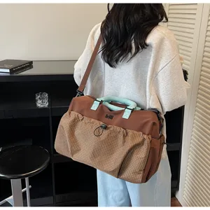 Detail view of large travel duffle bag carried on back, featuring brown plaid front pocket.