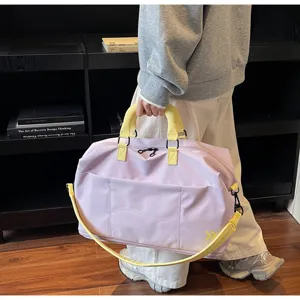 Travel duffel bag close-up showing purple fabric, yellow handles, and front pocket detail.