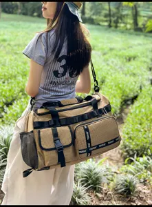 Detailed view of large capacity canvas travel gym bag in khaki grid with multiple pockets outdoors.