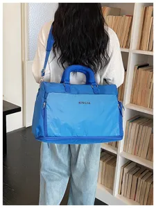 Grand sac de voyage bleu avec poche avant, idéal pour les courts séjours et le sport.