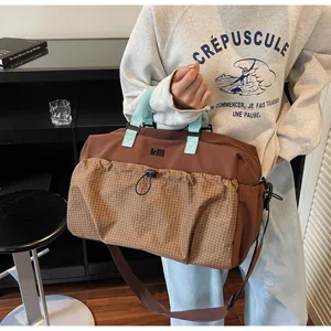 Large capacity duffel bag with brown grid front pocket and blue handles, ideal for travel.