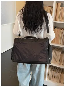 Grand sac de voyage noir avec bandouliere reglant et poches laterales pour courts sejours.