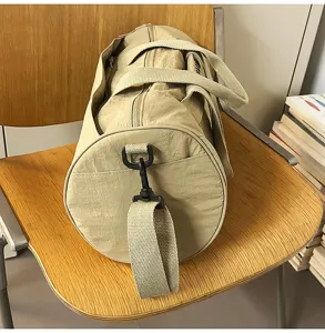 Khaki cylindrical sports gym duffel bag with shoulder strap for travel and fitness use.