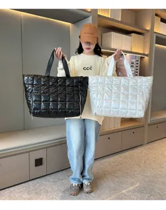 Model holding black and white quilted puffer tote bags in a stylish indoor display setting.