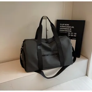 Vue détaillée du sac de voyage gris foncé avec de solides anses noires et une poche zippée.