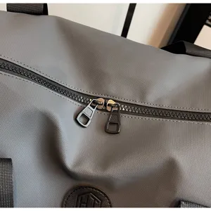 Détail en gros plan du sac de voyage gris avec un tissu très résistant et des fermetures zippées.