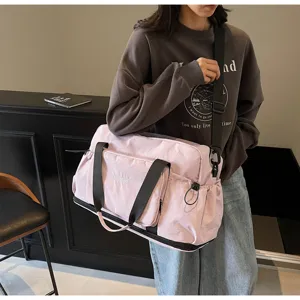 Detailansicht der rosa Reisetasche mit Vordertasche und Schultergurt am Model getragen.