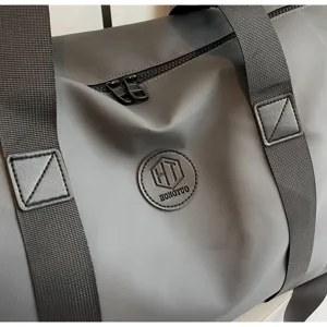 Gros plan détail du sac de sport de voyage gris avec des sangles noires et un tissu imperméable.