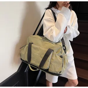 Detailansicht der hellgrünen Reisetasche mit schwarzen Gurten und geräumiger Fronttasche.