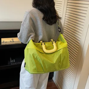 Detalle de bolso de viaje grande verde, bolsa deportiva informal con asas prácticas.