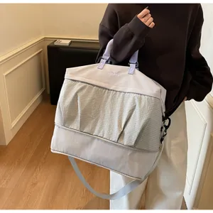 Gran bolsa de viaje tipo duffel con elegante bolsillo delantero plisado y cómodas asas moradas.