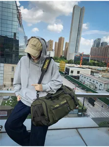 Vista di dettaglio della grande borsa da viaggio verde militare con tracolla in esterno urbano.