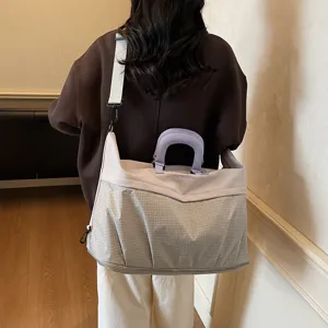 Bolso de viaje grande con patrón de cuadros, correa para el hombro y asa violeta.