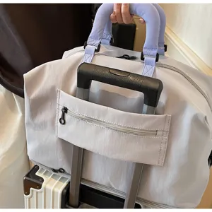Detalle de bolsa de viaje grande con cinta para maleta y cómodas asas moradas.