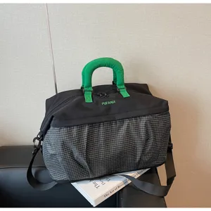 Vista detallada de la gran bolsa de viaje con diseño negro y verde y asas resistentes.