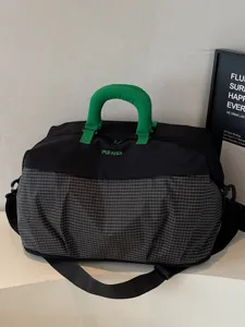 Grand sac de voyage avec poignées vertes et motif à carreaux pour les courts séjours.