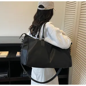 Vista dettagliata della grande borsa da viaggio nera che mostra il suo stile e la tracolla.