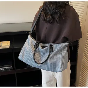 Dettaglio della borsa da viaggio in tessuto spigato resistente e manici neri.