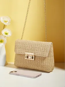 Vista detallada de un bolso cruzado de paja dulce con una elegante correa de cadena metálica.