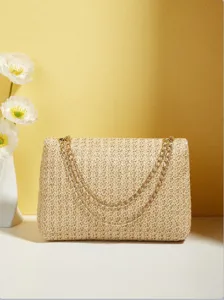 Detalle de bolso de hombro de paja chic con material texturizado y correa de cadena dorada.