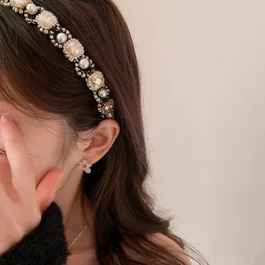 Detailed close-up of a luxurious pearl and crystal rhinestone headband and flower earrings.