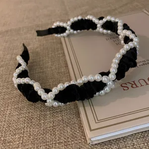 Gedetailleerd overzicht van de elegante vintage haarband in zwart fluweel met parels.