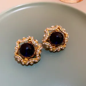 Detailed close-up of vintage gold clip-on earrings with deep blue center and crystal rhinestones.