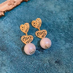 Vintage hollow heart pearl drop earrings detail shot, elegant court style alloy ear studs.